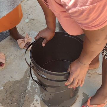 Pushing a bucket onto the laundry in the bucket with holes